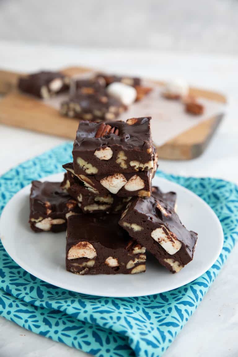 A stack of sugar-free keto fudge on a white plate over a blue patterned napkin.