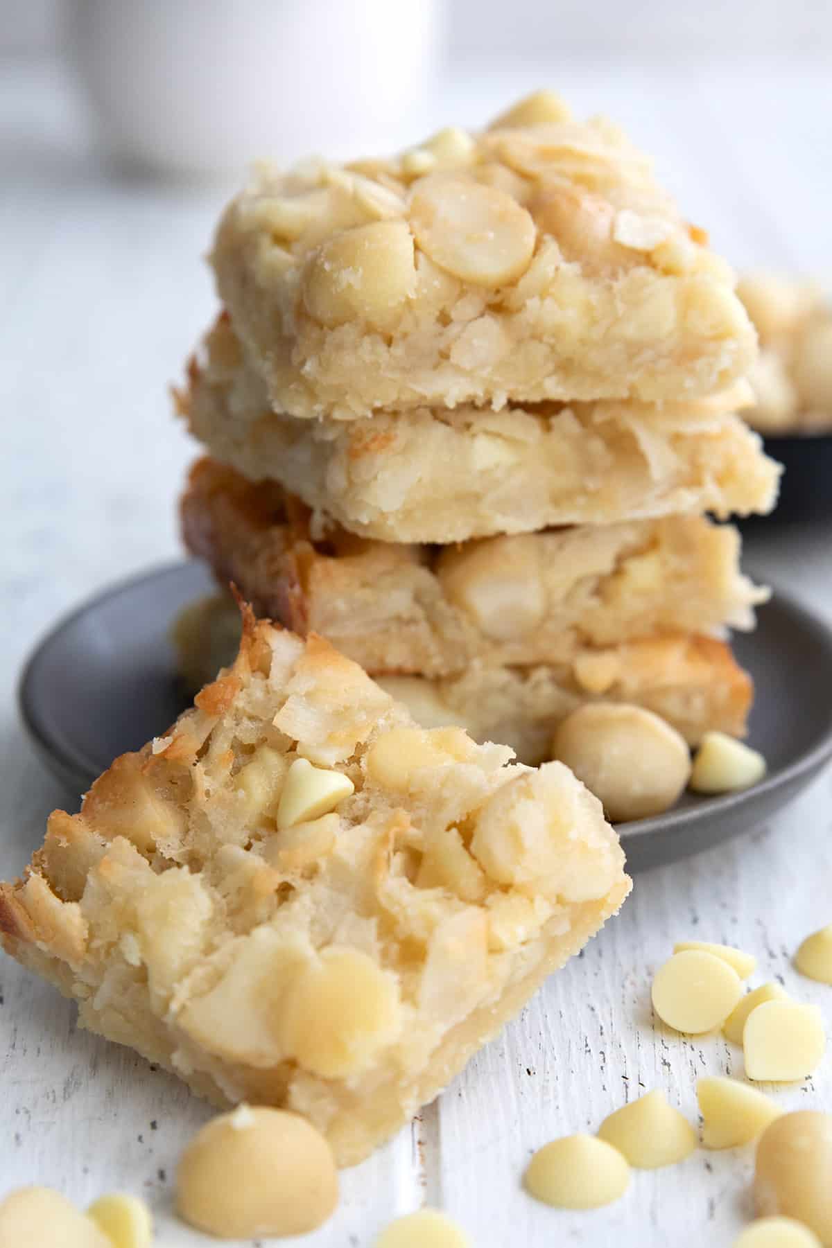 Keto Coconut Macadamia Bars stacked up on a white table with one in front.