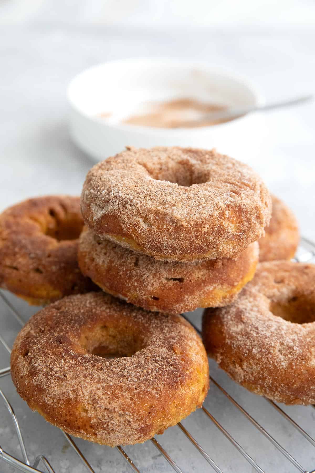 A pile of Keto Pumpkin Spice Donuts on a cooling rack.