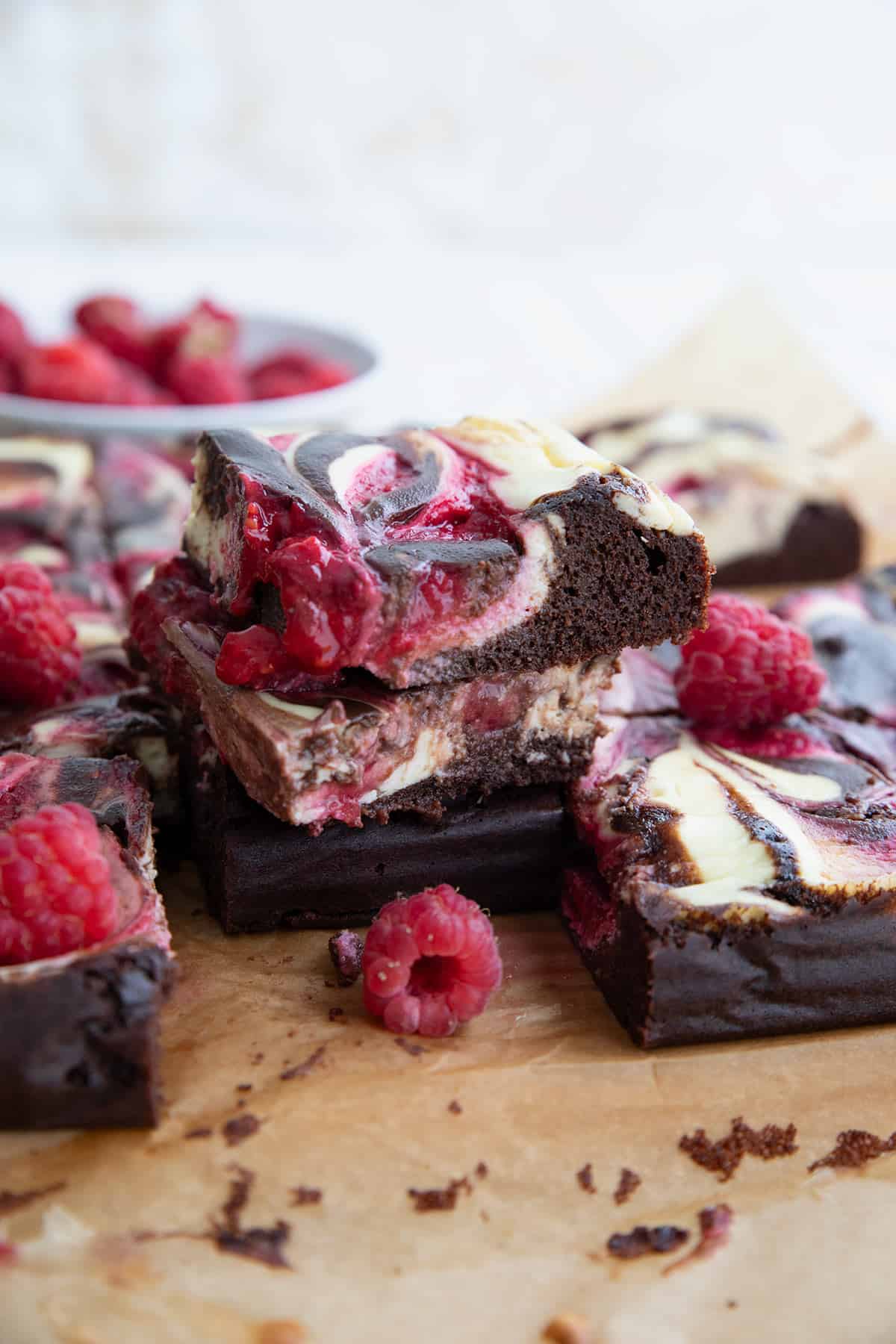 A pile of Keto Raspberry Cheesecake Brownies on parchment paper.