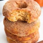 Titled Pinterest image of a stack of Keto Pumpkin Donuts on a white plate, with a bite taken out of the top one.