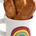 Titled image of keto biscotti standing up in a white mug with a rainbow on the front.