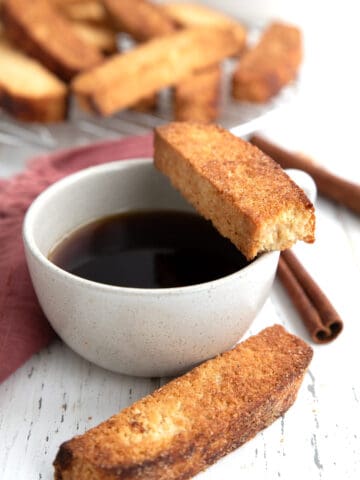 Keto biscotti around a cup of coffee with a bite taken out of one.