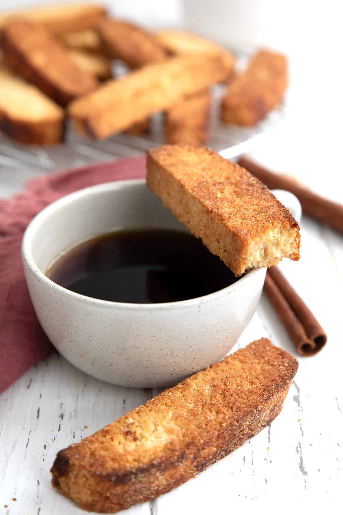 Keto biscotti around a cup of coffee with a bite taken out of one.