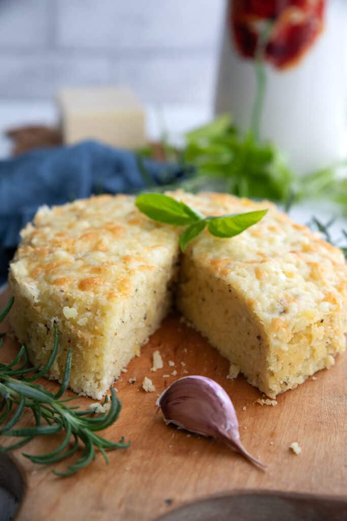 Keto Instant Pot Garlic Bread on a wooden cutting board with herbs placed around it.