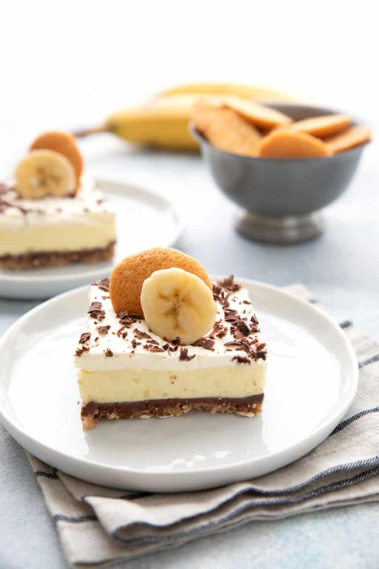 A Keto Banana Cream Pie Bar on a white plate with vanilla wafers in the background.