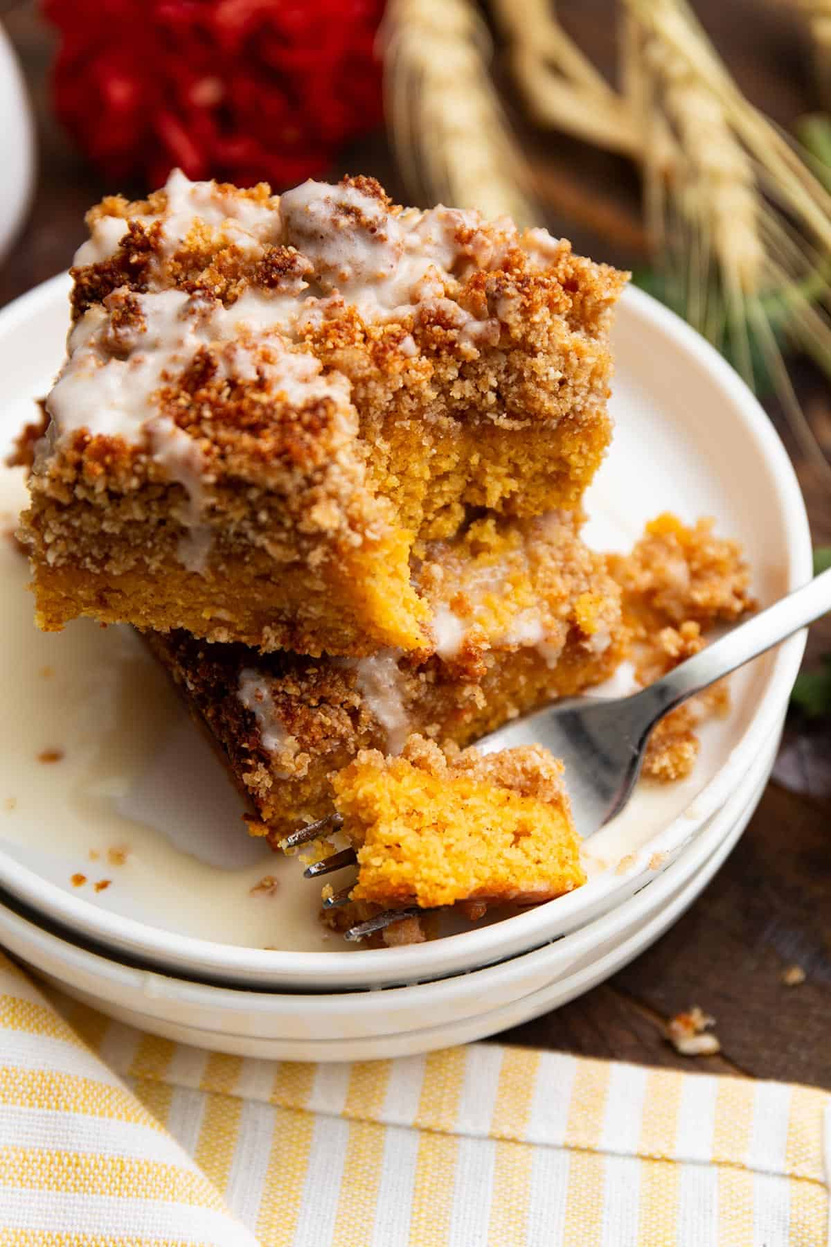Two pieces of Keto Pumpkin Crumb Cake on a white plate with a forkful taken out of one.