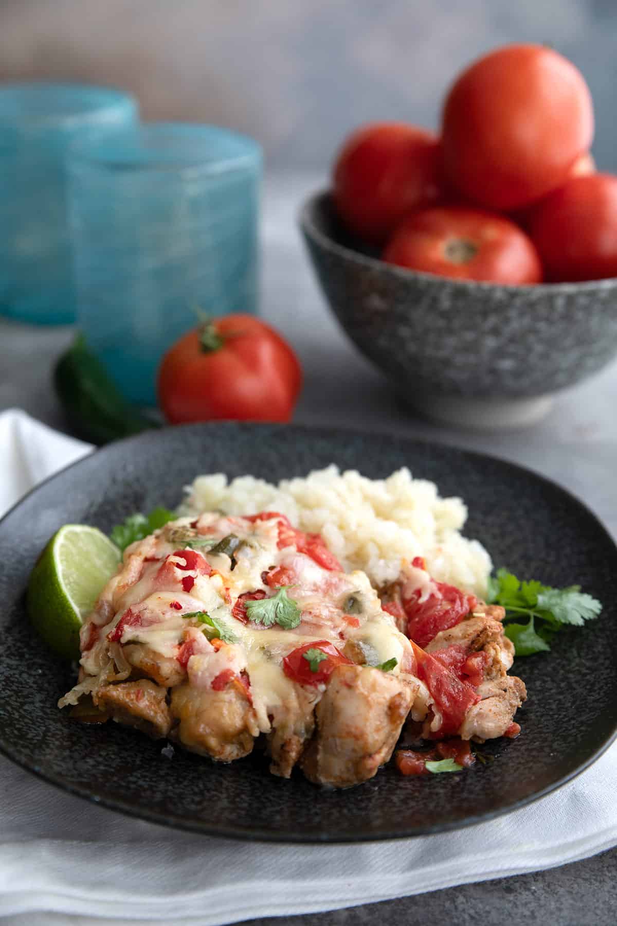 Salsa Fresca Chicken Bake on a plate with cauliflower rice, with a bowl of tomatoes in the background.