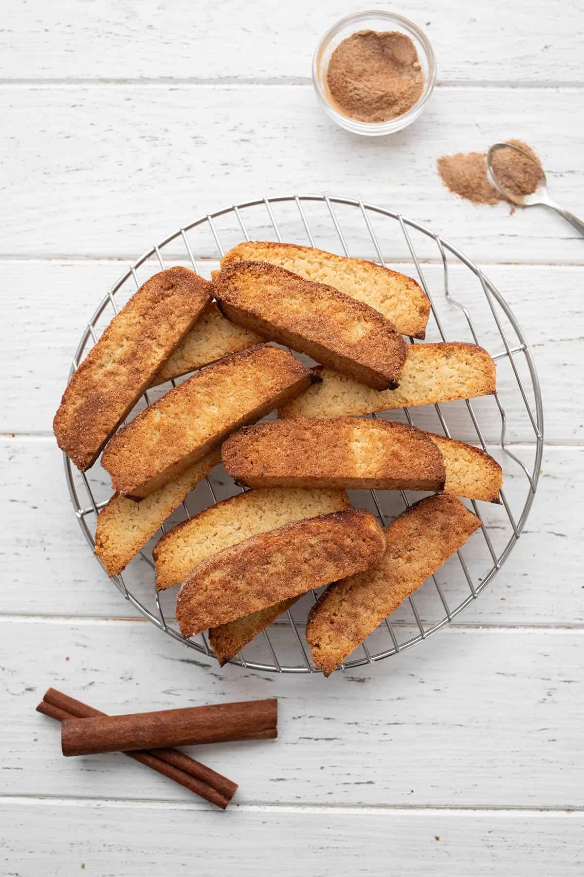 Top down image of keto biscotti on a cooling rack over a white wooden table.