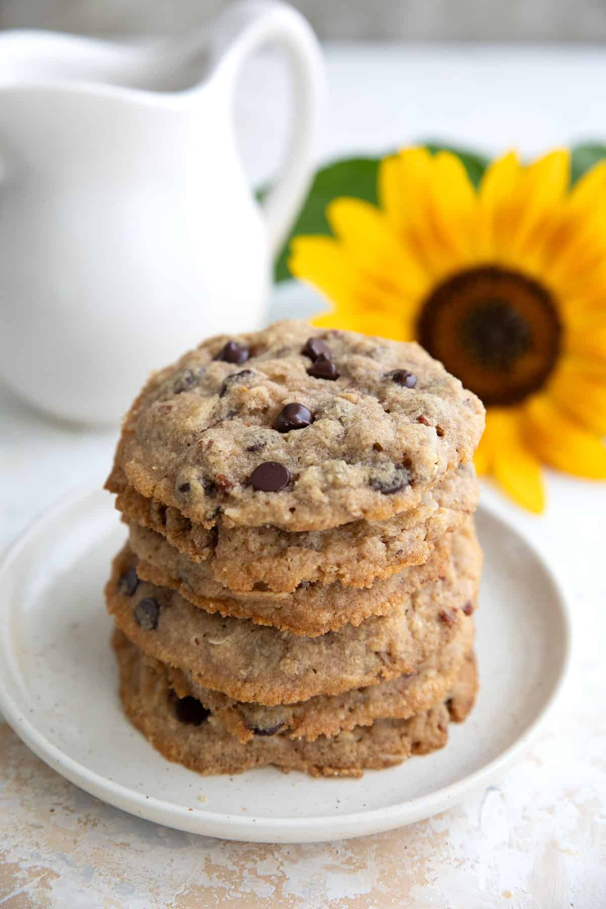 A stack of Keto Cowboy Cookies on a white plate with a sunflower in the background.