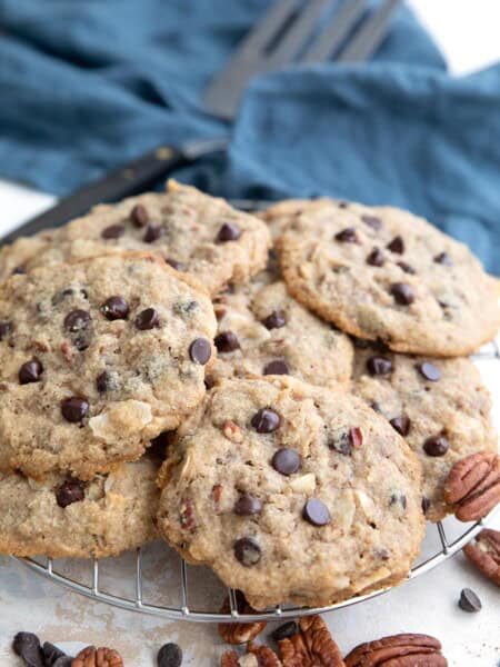 Keto Cowboy Cookies in a pile on a cooling rack with a blue napkin in the background.