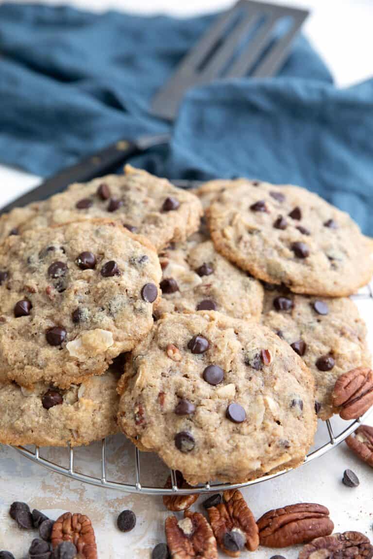 Keto Cowboy Cookies in a pile on a cooling rack with a blue napkin in the background.