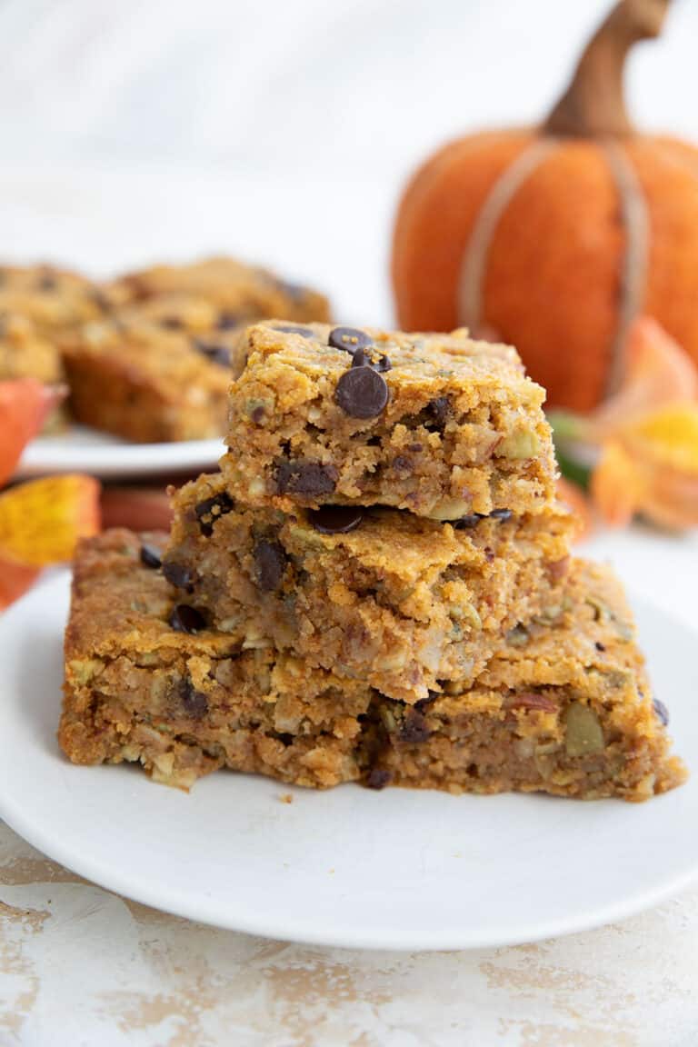 A stack of Keto Pumpkin Breakfast Bars on a white plate in front of a felt pumpkin.