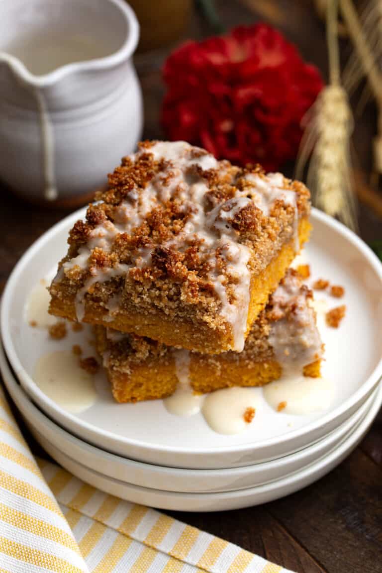 Two Keto Pumpkin Crumb Cake on a stack of white plates with a yellow striped napkin.