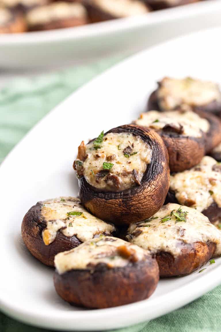 Stuffed mushrooms arranged on a white oval serving platter.