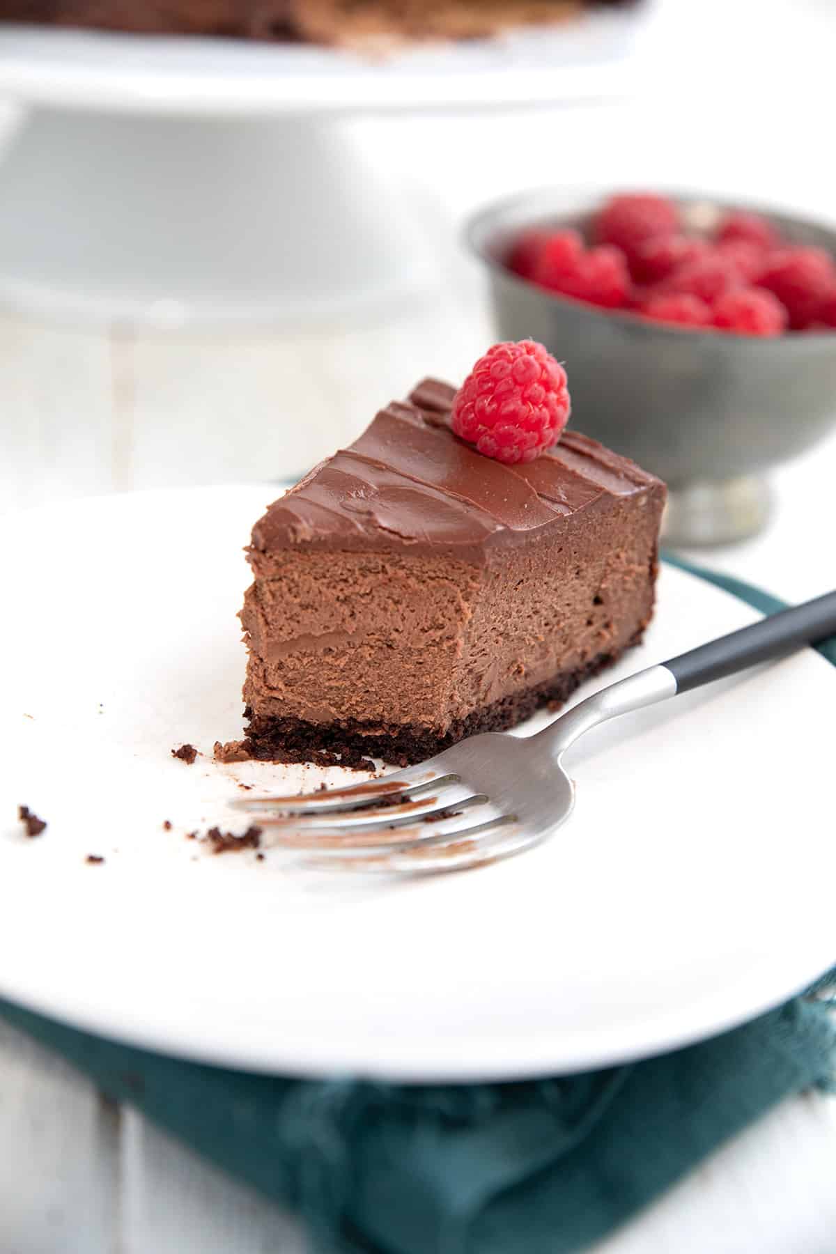 A slice of Keto Chocolate Cheesecake on a white plate with several bites taken out of it.