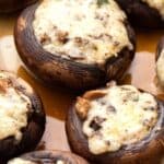 Titled image of cheese stuffed mushrooms on a brown serving plate.
