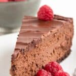 Titled Pinterest image of a slice of keto chocolate cheesecake with fresh raspberries.