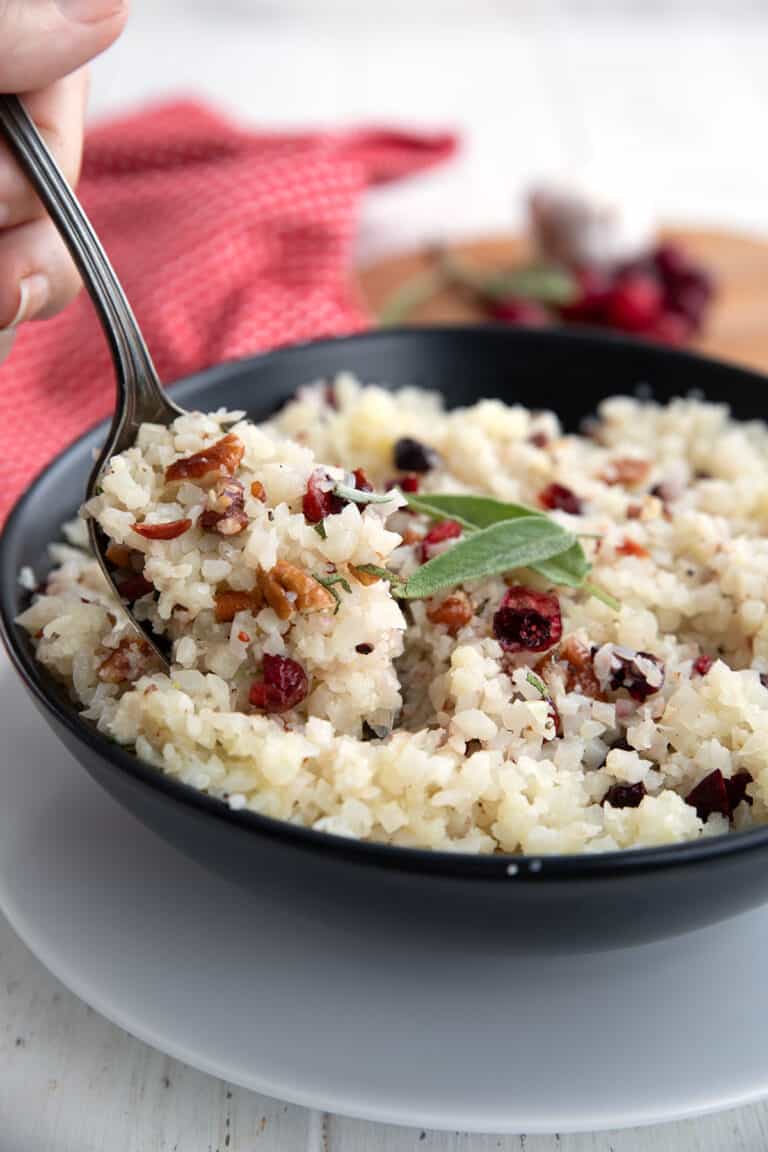 Keto Rice Pilaf in a black bowl with a spoonful being lifted out of it.