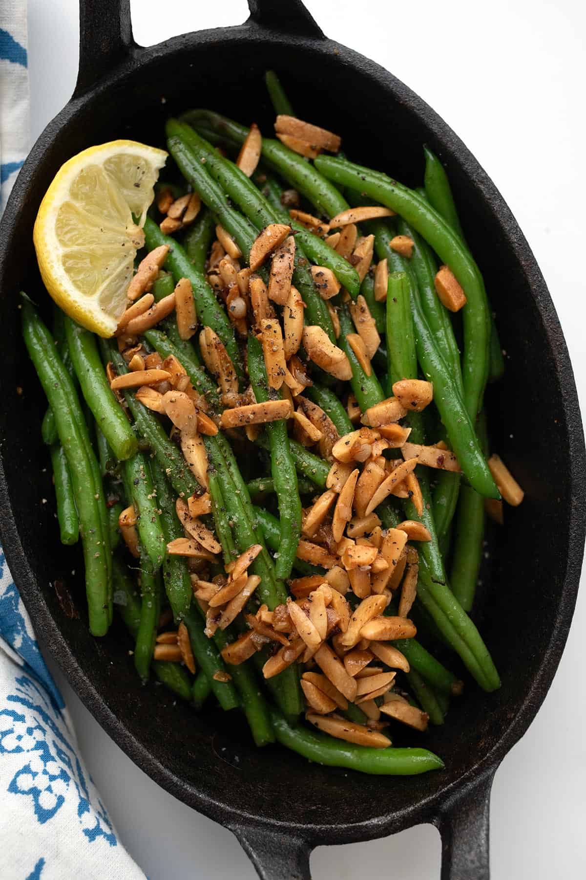 Top down image of Green Beans Almondine in an oval cast iron dish.