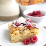 A serving of Keto French Toast Casserole on a white plate over a muted red napkin.