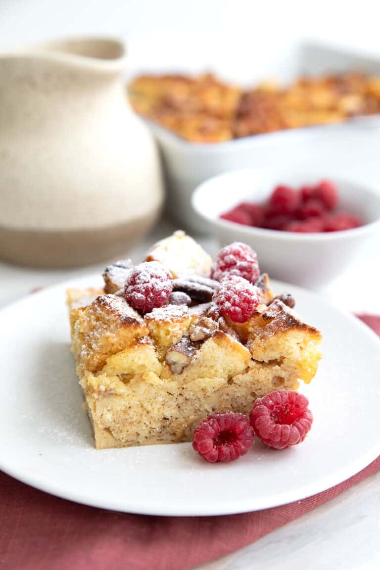 A serving of Keto French Toast Casserole on a white plate over a muted red napkin.