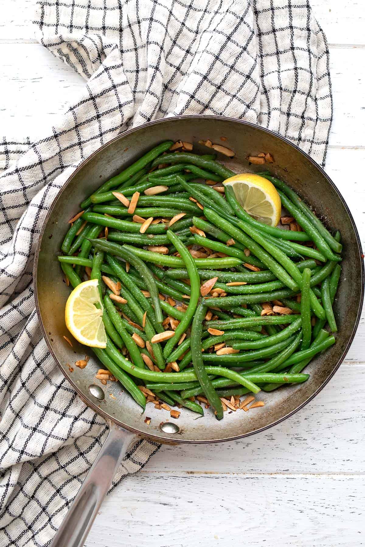 Top down image of Green Beans Almondine in a skillet on a white table.