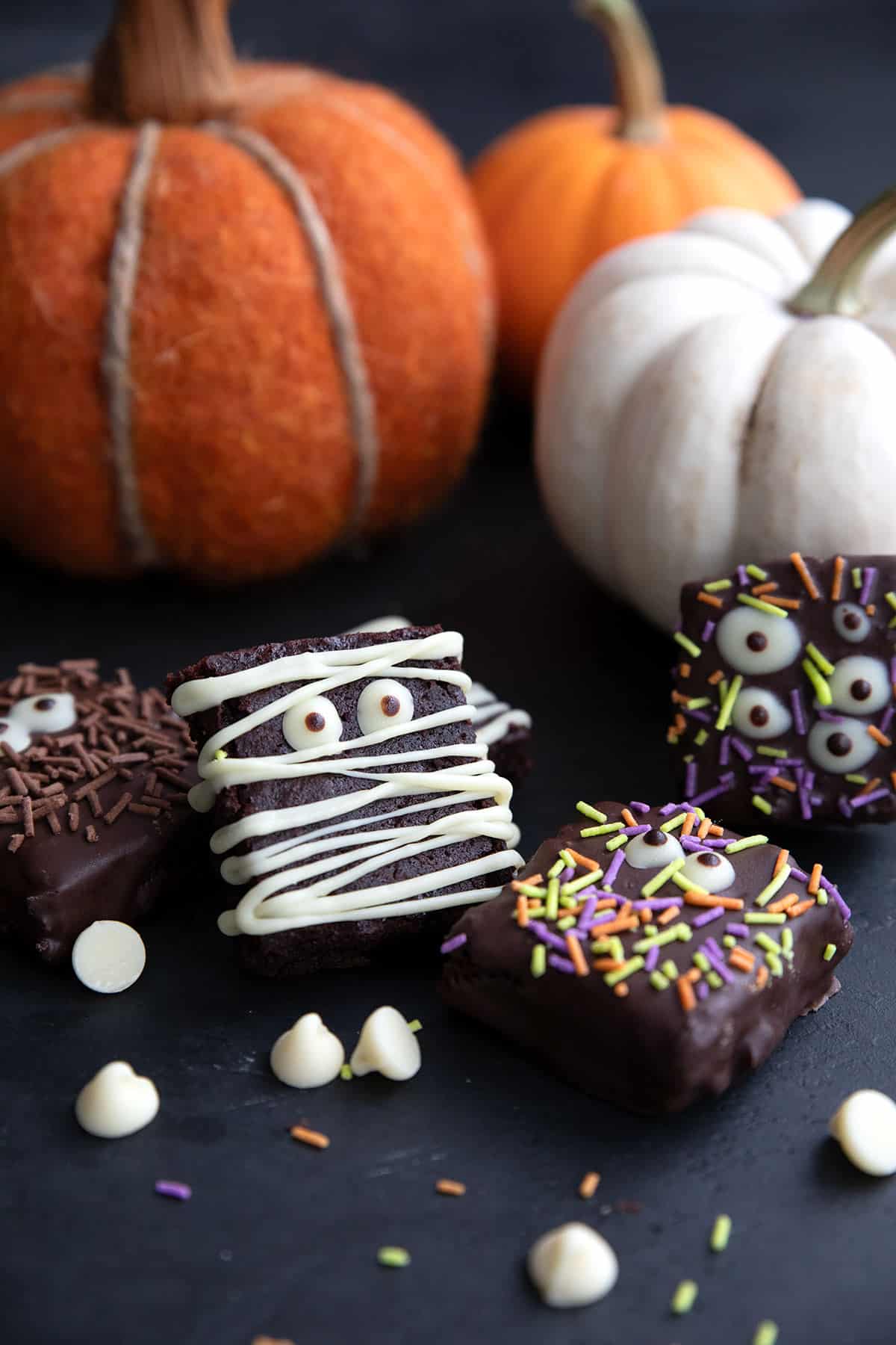 Keto Halloween Brownies decorated like mummies and monsters with pumpkins in the background.