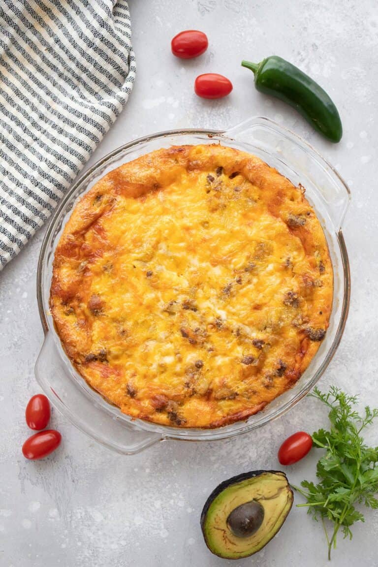 Top down image of freshly baked Taco Pie with tomatoes, jalapeño, and avocado around it.