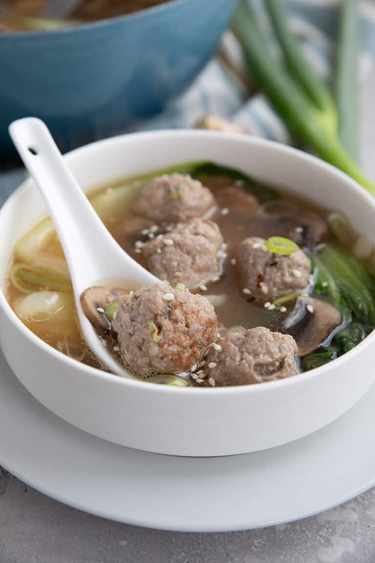 Keto Wonton Soup in a white bowl with a white ceramic spoon.