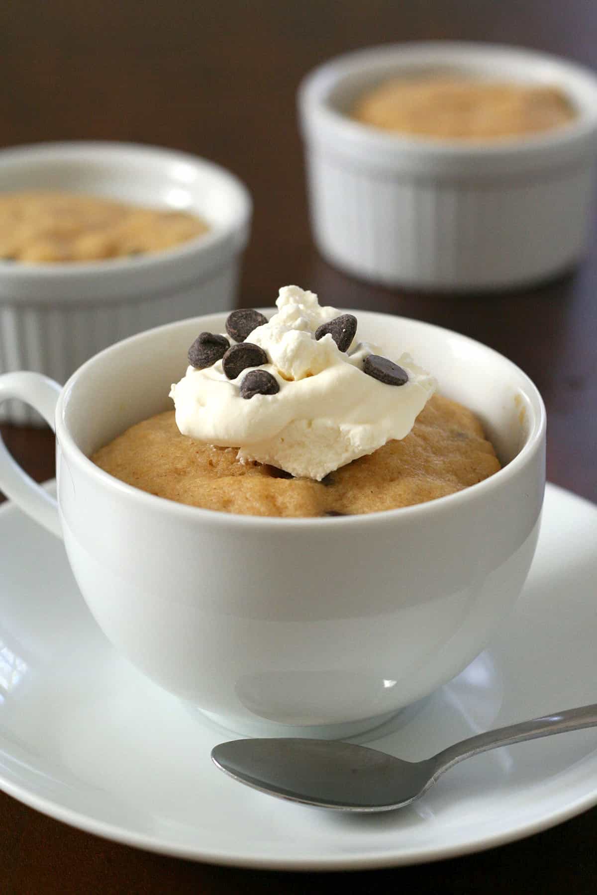A peanut butter keto mug cake in a white porcelain coffee cup on a white saucer.