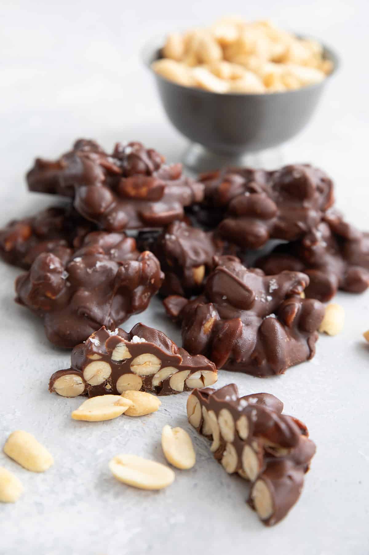 A pile of Keto Peanut Clusters on a concrete table, with one cut open to show the inside.