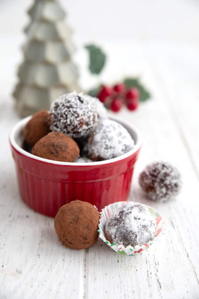 Keto Rum Balls in a red ramekin on a white table with two in front.