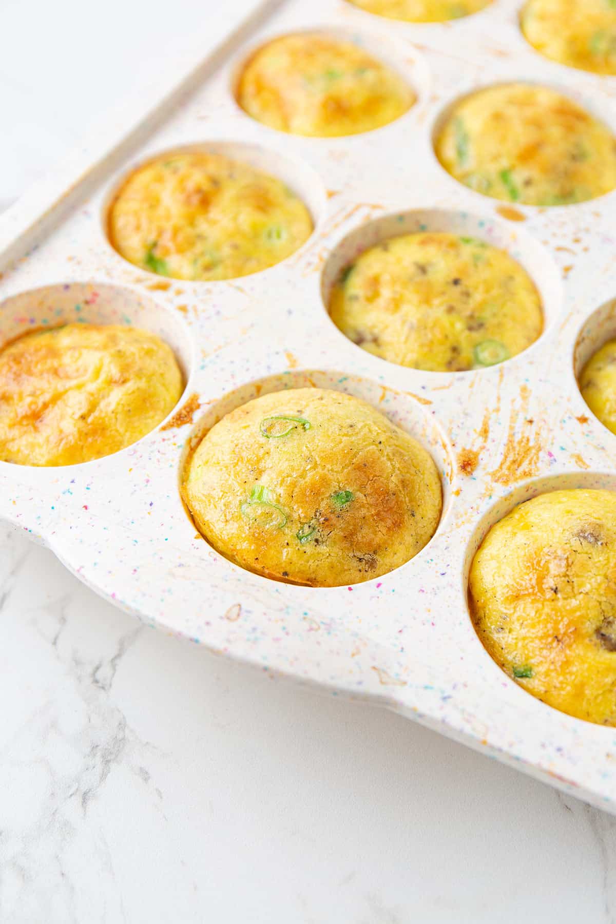 Freshly baked egg muffins in a white silicone pan on a marble table top.