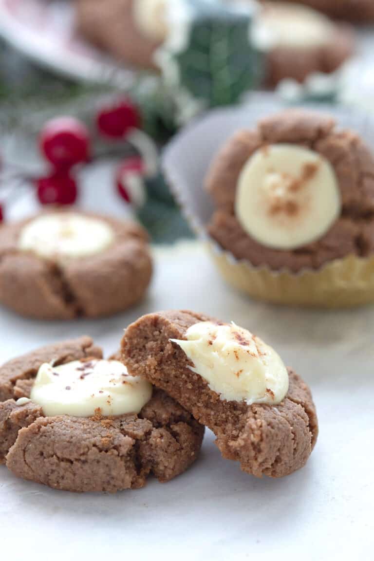 Keto Gingerbread White Chocolate Thumbprint Cookies on a white table with a bite taken out of one.