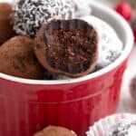 Close up shot of keto rum balls in a red ramekin with a bite taken out of one.