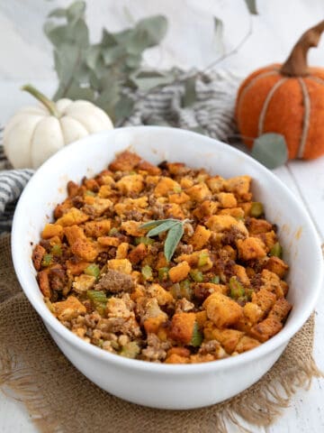 Keto Stuffing in an oval baking dish in front of pumpkins and Thanksgiving decorations.