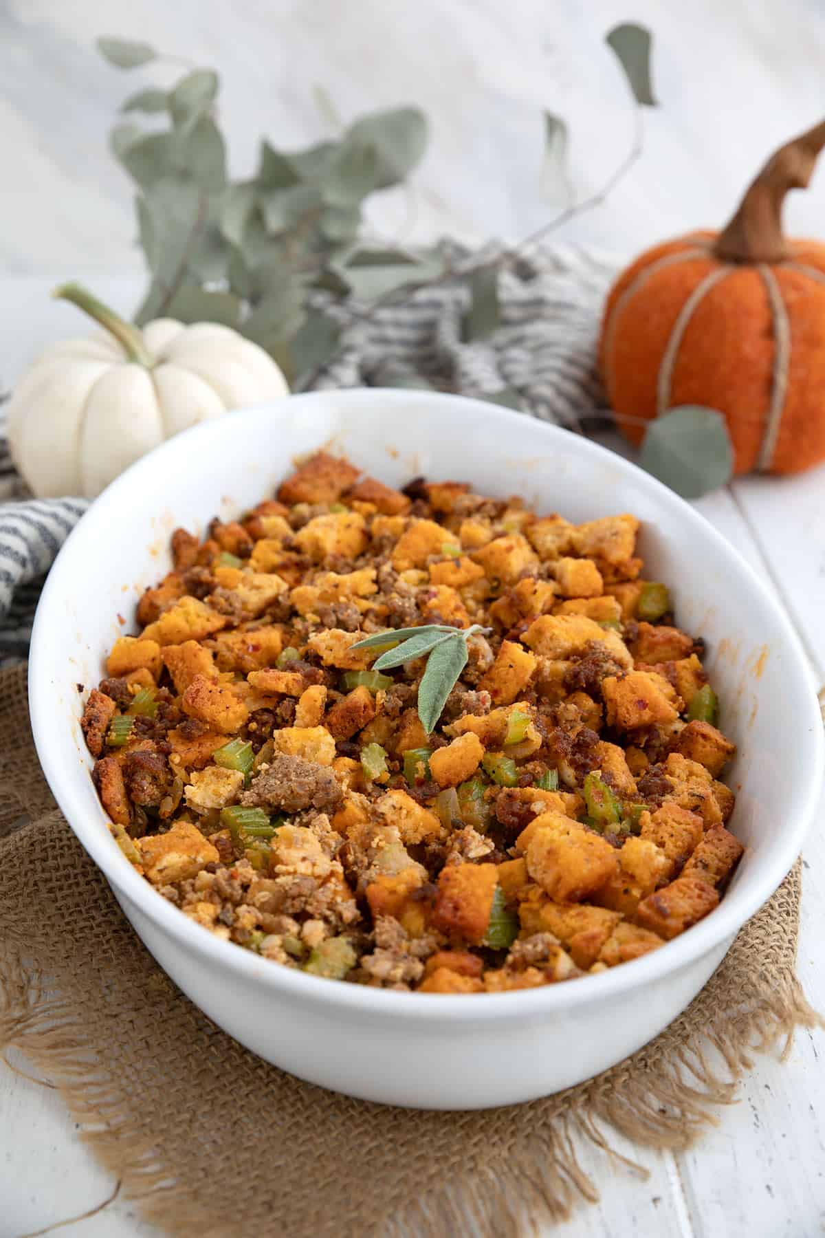 Keto Stuffing in an oval baking dish in front of pumpkins and Thanksgiving decorations.