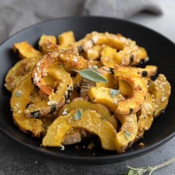 A black bowl filled with Roasted Delicata Squash.