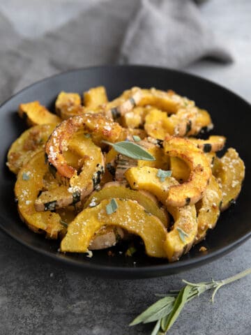 A black bowl filled with Roasted Delicata Squash.