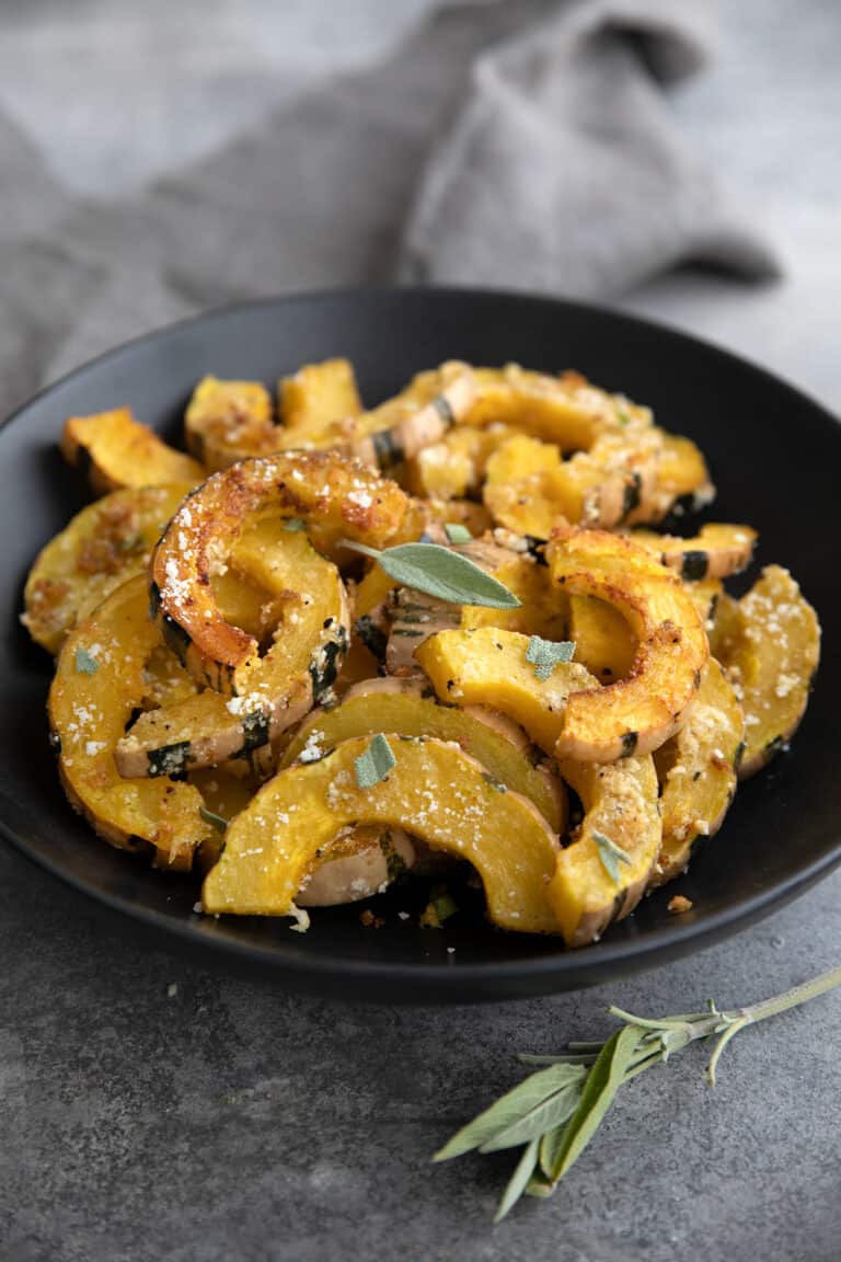 A black bowl filled with Roasted Delicata Squash.