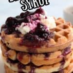 Titled Pinterest image of keto waffles in a stack with sugar-free blueberry syrup being poured out of a small white pitcher.