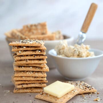 A stack of keto crackers on a brown table with Boursin cheese beside it.