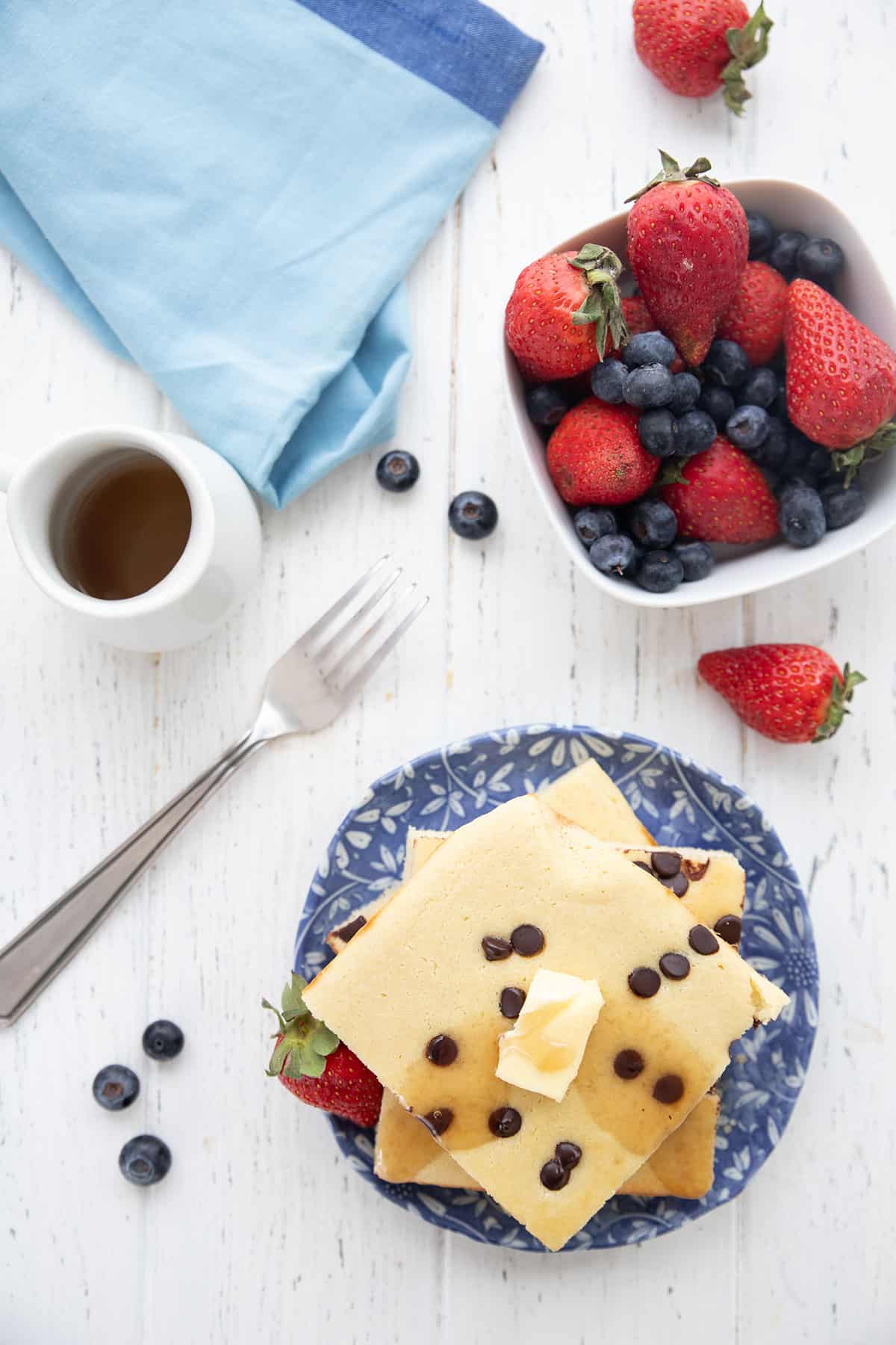 Top down image of a stack of Keto Sheet Pan Pancakes with a bowl of berries.