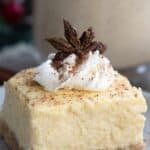 Close up shot of a keto eggnog cheesecake bar with whipped cream and ground nutmeg on top.