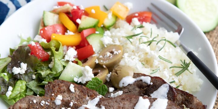 A keto gyro bowl with cauliflower rice and feta dressing in a white bowl.