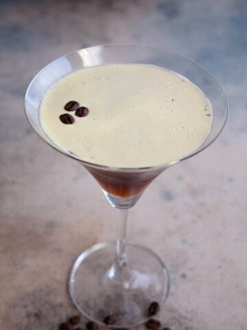 A single espresso martini on a weathered table.
