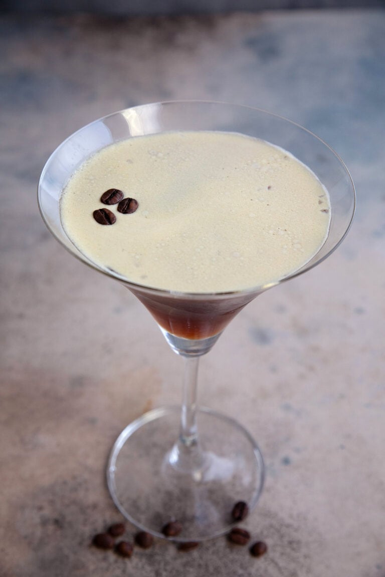 A single espresso martini on a weathered table.