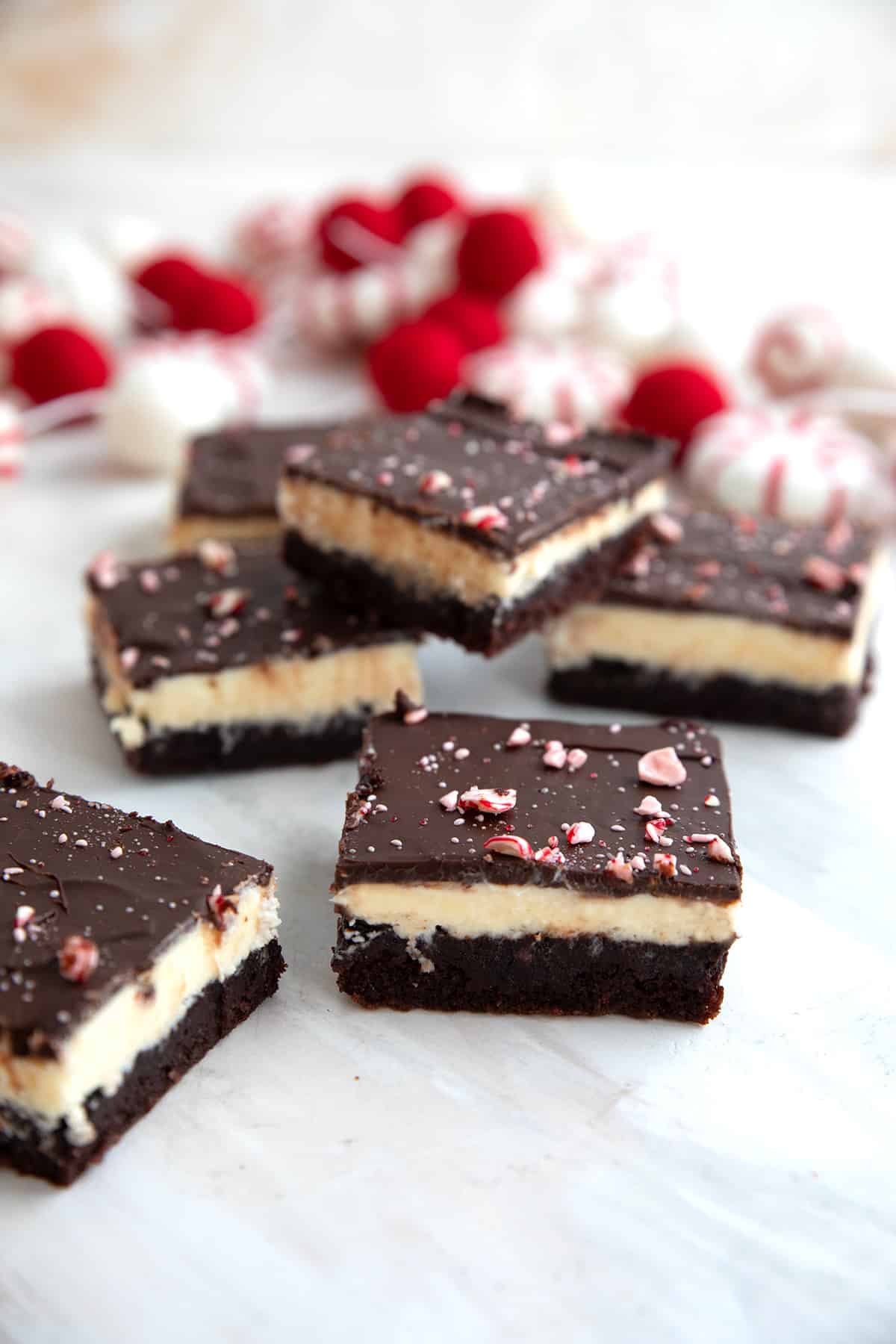 Keto Peppermint Bark Brownies on a white table with holiday decorations in the background.