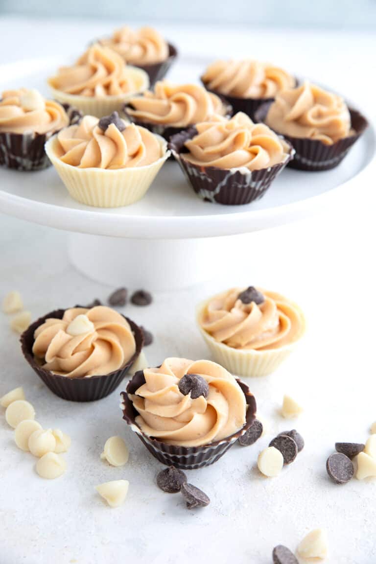 Mini Chocolate Dessert Cups filled with keto peanut butter mousse arranged on a white table and cake stand.